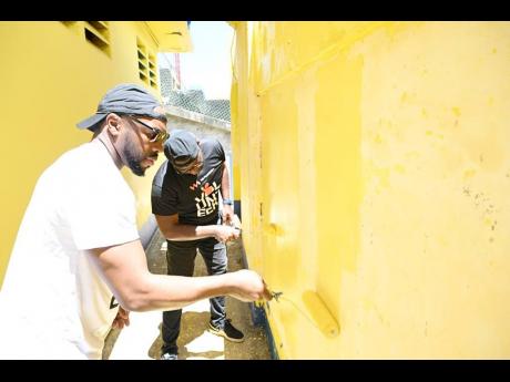 Fitzroy Thompson (left), project manager at the VM Group, and Andre Robb (right), programme lead at the VM Foundation, paint a wall at the Harbour View Football Stadium. They were participating in the VM Group 2024 Labour Day project, where more than 60 te