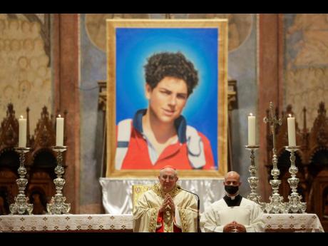 An image of 15-year-old Carlo Acutis, an Italian boy who died in 2006 of leukaemia, is seen during his beatification ceremony celebrated by Cardinal Agostino Vallini, centre, in the St. Francis Basilica, in Assisi, Italy, on October 10, 2020. 