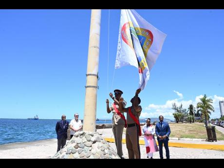 Staff Sergeant Anthony Gardner (third left) and Staff Sergeant Christopher Maitland raise the ‘HMT Empire Windrush’ standard during a ceremony on Friday to mark the 76th anniversary of the departure of the vessel from Kingston. Looking on (from left) a