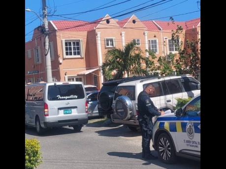 A member of the Jamaica Constabulary Force is seen just outside the home of the late Dr Daniel Dawes, former CEO of the Universal Service Fund, on Friday. Dawes was found dead at his home in Stadium Gardens, St Andrew, on Friday.