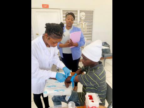 Afiene Morgan (right) carefully inserts the needle while her lecturer Mohni Mitchell supervises