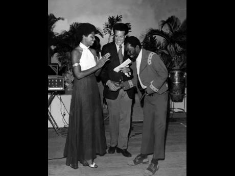 JOE HIGGS WINS: Mrs. Michael Manley and Mr. Anthony Abrahams, Director of Tourism congratulate Joe Higgs after the judges voted his song ‘Invitation to Jamaica’, the best entry in the tourism song contest at the Regal Theatre, on November 27, 1972. He 