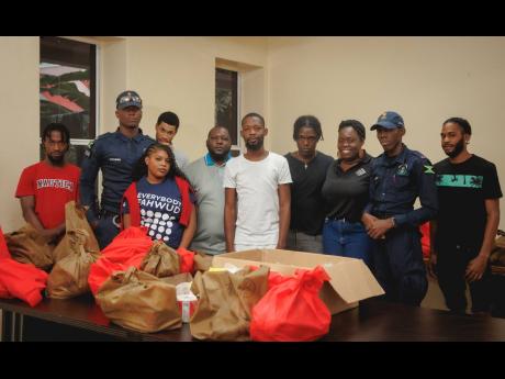 Members of the community of Parade Gardens, team members from Project STAR and the Jamaica Constabulary Force prepare care packages for vulnerable persons in the community.