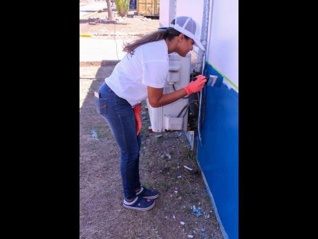 Ashley Chin, Acting vice-president of Group Culture & Talent, adds to the beautification of the Search Center at the National Police College of Jamaica during Labour Day activities.