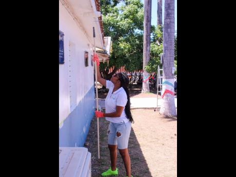 First Rock’s Senior Manager of Group Marketing, Sable-Joy McLaren, getting hands-on during Labour Day at the National Police College of Jamaica on Thursday. 
