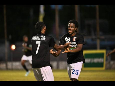 August Town players Jevoney Johnson (left) and David Jacob celebrate the team’s go-ahead goal against Duhaney Park FC during the KSAFA Major League final at the Anthony Spaulding Sports Complex yesterday.