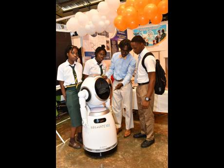 Dr Damian Graham (third left), programme director for the industrial and mechanical engineering programme at The University of Technology, Jamaica, explains the operations of a robot to three high school students at an open house hosted by the university l