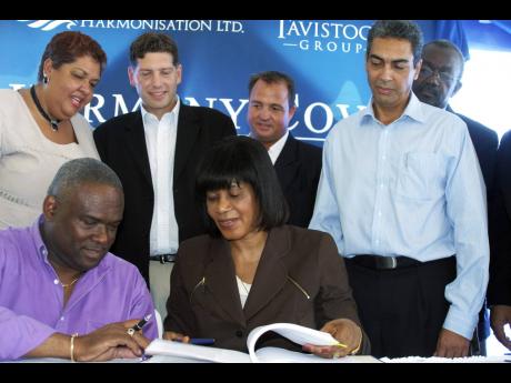 In this 2006 Gleaner photo, Prime Minister Portia Simpson Miller and Information and Development Minister Colin Campbell leaf through an agreement between Tavistock Group of Florida and Harmonisation Limited before signing, as Chris Anand (second left, sta