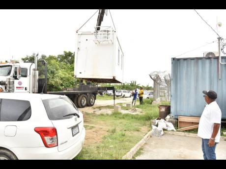 Howard Ward, founder of Ward’s Power Tools and Supplies Limited, observes his his staff offloading a 20x10 mobile container office his company donated to the St James Special Operations Team at the St James Police Divisional Headquarters in Freeport, Mon