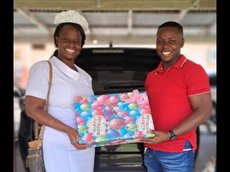 Dorcia Brown-Lyle (left), a nurse at the Black River Hospital in St Elizabeth and creator of the New BIRTH programme which is operated at the hospital, presents a donation package to Romain Johnson, the father of a new mother who gave birth at the hospital