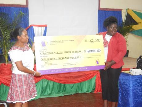 A super-sized cheque for $140,000.00 is displayed by principal of the Louise Bennett-Coverley Primary School, Sheena Taylor Morgan (left) and the school’s Cultural Agent Patricia Grindley. 