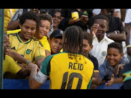 Reggae Boyz midfielder Bobby de Cordova-Reid greets some young fans at the National Stadium on Thursday after Jamaica defeated the Dominican Republic 1-0 in a 2026 World Cup qualifying match. 