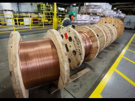 A worker looks at rolls of copper wire at Nexans, one of the world’s largest wire and cable manufacturers, Friday, April 12, 2024, near Montreal. The company is mixing more and more scrap copper into its products.