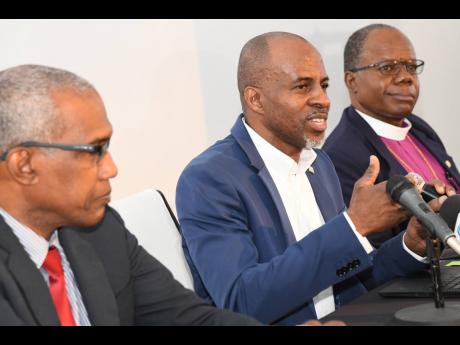 In this February 2023 photo, Lloyd Distant (centre), CMOC chairman, speaks to members of the media while Commander George Overton (left) and Bishop Garth Minott look on. 