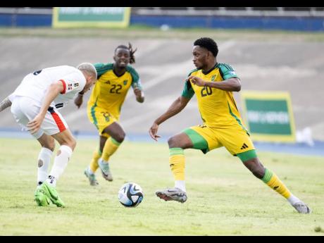 Jamaica’s Renaldo Cephas (right) marked by Edarlyn Reyes (left) of Dominican Republic during their match at the National Stadium, Kingston.