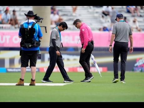 Officials inspect the field before an ICC Men’s T20 World Cup cricket match between the United States and Ireland at the Central Broward Regional Park Stadium in Lauderhill, Florida, yesterday.  Rain forced a no-result between United States and Ireland. 