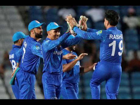Afghanistan’s wicket keeper Rahmanullah Gurbaz (third from left)  celebrates with captain Rashid Khan after the dismissal of Papua New Guinea’s Lega Siaka during an ICC Men’s T20 World Cup cricket match at Brian Lara Cricket Academy in Tarouba, Trini