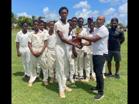 The Inter-Secondary Schools Sports Association’s competitions director Ewan Scott (right) presents the winning  trophy to St Elizabeth Technical’s captain Eckoney Robinson following their six-wicket win over Manchester High in yesterday’s under-14 fi