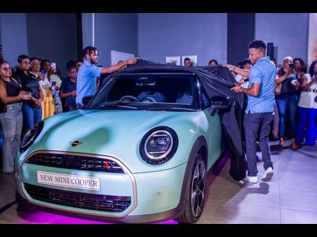 Service Advisor  Daniel   Britton   and  Sales Executive   Jabari   Marshall  unveil the new MINI Cooper S in Ocean Wave Green,  an   exclusive   colour  only  available  in this new generation of MINI Coopers. 