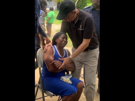 National Security Minister Dr Horace Chang consoles Marlene Nation, who lost her son and grandson to gun violence in Johnson Town, Hanover, last week.