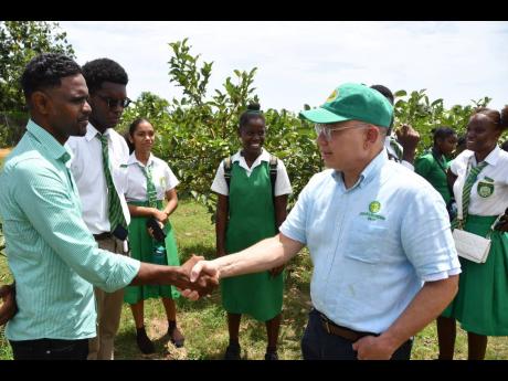 Collin Chen, teacher of environmental science and agricultural science at St Mary High School, is greeted by Jeffrey Hall (right), CEO and deputy chairman at Pan Jamaica Group. Looking on are students of St Mary High School who were part of a group that we