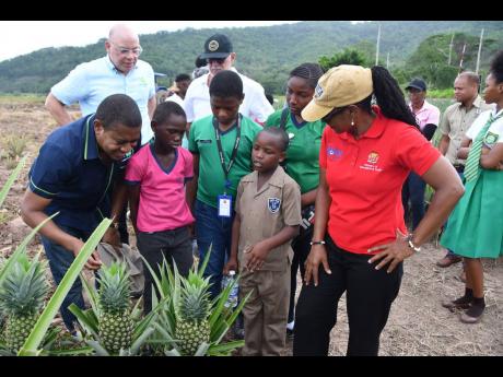 Ke-Adonique Brown, grade four student of White Marl Primary School, commands the attention of Agriculture Minister Floyd Green (left) and Education State Minister Marsha Smith (right) and his peers (Davion Thomas, Malcolm Lawrence and Alexandria Campbell).