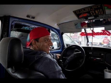 Taxi driver Claudio Garcia sits inside his Volkswagen Beetle he has named “Gualupita” after his wife.