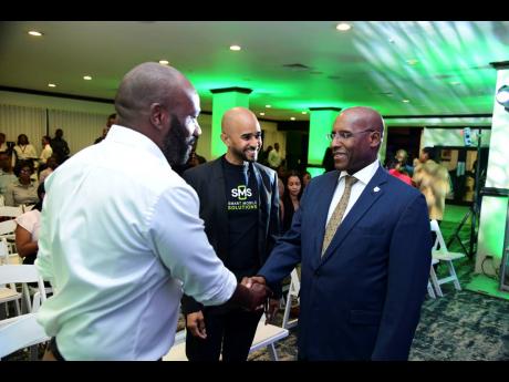 Co-Founder and Director of the Smart Mobile Solutions Group Marlon Hudson (left) and Co-Founder and Managing Director of the Smart Mobile Solutions Group Dane Spencer (centre) greet Minister of Industry, Investment and Commerce Senator Aubyn Hill during th