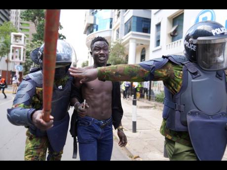 Kenyan riot police arrest a man during a protest over proposed tax hikes in a finance bill in downtown Nairobi, Kenya, on Tuesday.