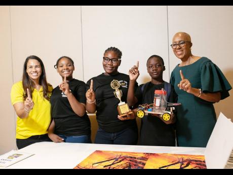 Fayval Williams (right), minister of education and youth, joins in a photo op with Lisa D’Oyen (left), executive director,  Seprod Foundation, and the winning team from George Headley Primary School in the Code Jamaica Expo: World Robot Olympiad Future I