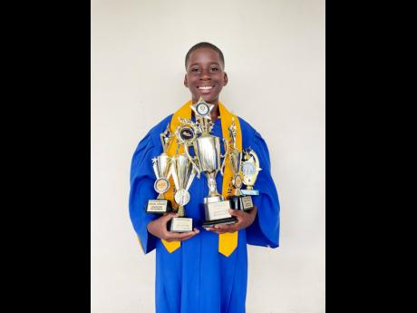 Johntae Peterkin cuddling the trophies he received for his performance during his final year at the Negril Primary School.