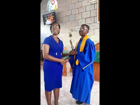 Johntae Peterkin (right), a final-year student at the Negril Primary, collects his Overall Top Primary Exit Profile Trophy from Margorian James, a grade six teacher.