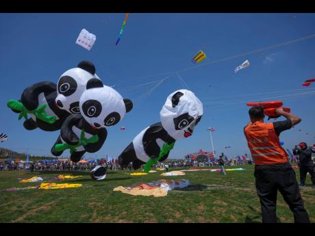A man gives air to panda-shaped kite during the 41st International Kite Festival in Weifang, Shandong Province of China.