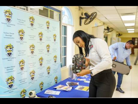 National Baking Company Foundation’s Lauri-Ann Samuels, keenly observes a robot on display at the  University of Technology’s STEM Summer Camp’s launch event. The event was held at the university’s western campus on Tuesday. 