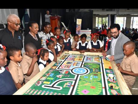 State Minister in the Ministry of Education and Youth, Marsha Smith (fifth left), looks on while robotics instructor, Zebra Robotics in Canada, Tahmoor Naeem (second right), conducts a robotics lesson with students from Bryce Primary School in Manchester. 