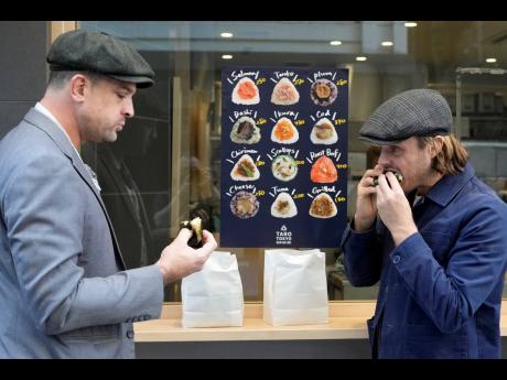 Tourists from Australia eat onigiri, rice balls, at a Taro Tokyo Onigiri shop.