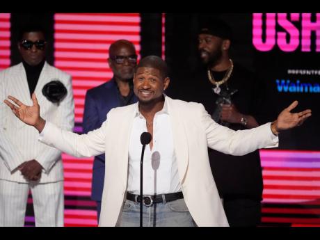 Usher accepts the Lifetime Achievement Award during the BET Awards on Sunday at the Peacock Theater in Los Angeles. Babyface (rear left) and L.A. Reid (rear centre) look on.