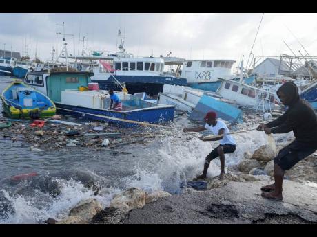 Fishermen pull a boat damaged by Hurricane Beryl back to the dock at the Bridgetown Fisheries in Barbados on Monday.