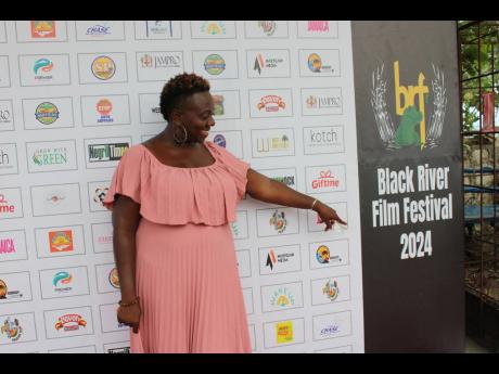 Festival Director Dr Ava Brown happily points to a Black River Film Festival sign, cherishing the realisation of her dream.
