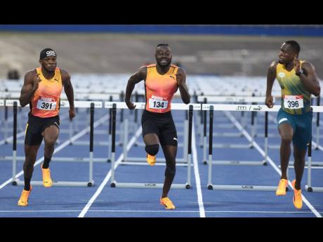Hansle Parchment (right) looks across at Rasheed Broadbell (centre) and Orlando Bennett during the JAAA/PUMA National Junior and Senior Championships on Sunday.