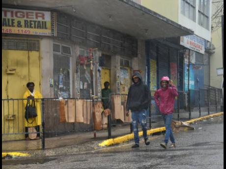People walk along St James Street in downtown Montego Bay after the intial effects of Hurricane Beryl were felt on Wednesday.