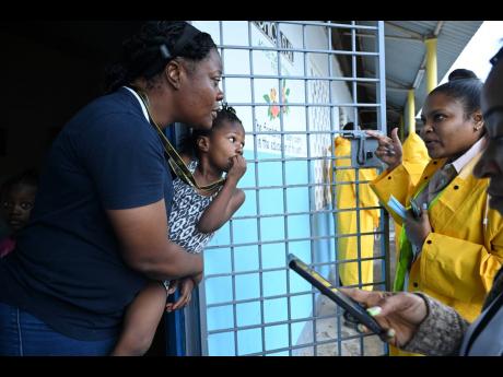 Public health inspectors speak to a mother and her children at the Papine High School emergency shelter in St Andrew as Hurricane Beryl moved closer to Jamaica on Wednesday morning.