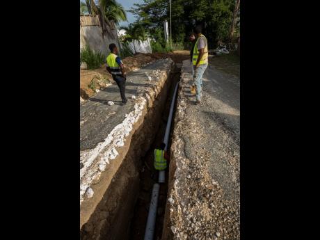 A man carries out work on a sewer pipe along Tavistock Terrace in Jacks Hill, St Andrew, on Thursday. The rushing waters from rainfall associated with Hurricane Beryl exposed the line, leaving a ditch.