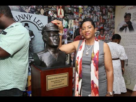 Annette Wong-Lee, the widow of Bunny Lee, poses next to a bust of him.