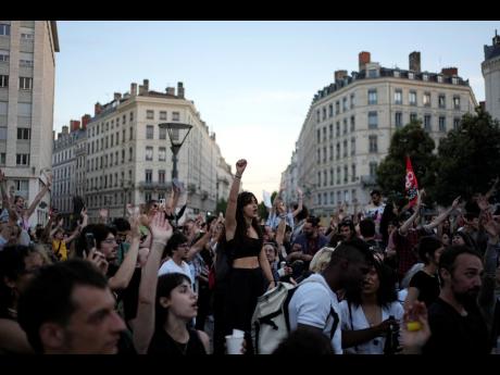 People stand in a square as they react to projected results after the second round of the legislative elections, in Lyon, central France, on Sunday.