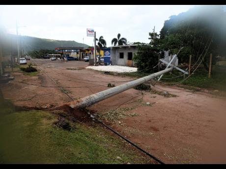 An uprooted Jamaica Public Service utility pole blocks the main road in Flagaman in St Elizabeth.
