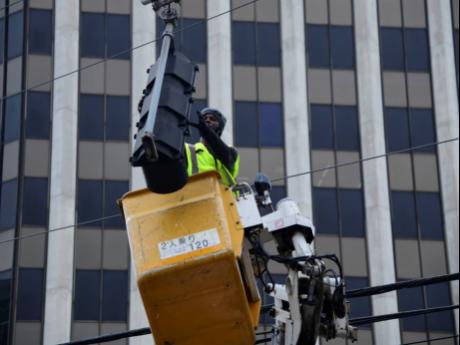 A man repairs a traffic light at the corner of Duke and Port Royal streets on July 7.