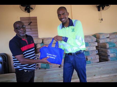 Caribbean Cement Company Limited’s Social Impact Specialist,  Jerome Cowans (right), presents Pastor Carlton Bryan of the Denbigh Church of the Nazarene, with a package of non-perishable food items at the Denbigh Church of the Nazarene in Woodside, Clare
