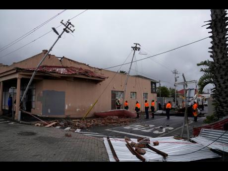 Rescue workers among damaged buildings in the Wynberg neighbourhood of Cape Town, South Africa yesterday.