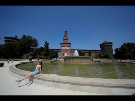 Tourists cool off at a fountain in front of the Sforzesco Castle in Milan, Italy, Thursday, July 11, 2024. A heat wave swept Italy on Thursday prompting health officials to issue a red alert for seven cities mostly in central Italy, including the capital R